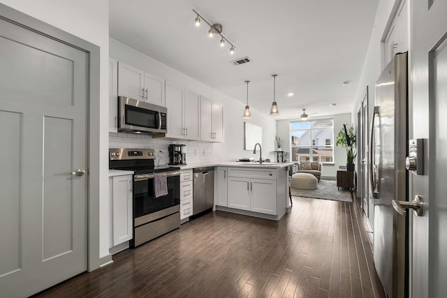 kitchen with visible vents, decorative backsplash, appliances with stainless steel finishes, a peninsula, and a sink