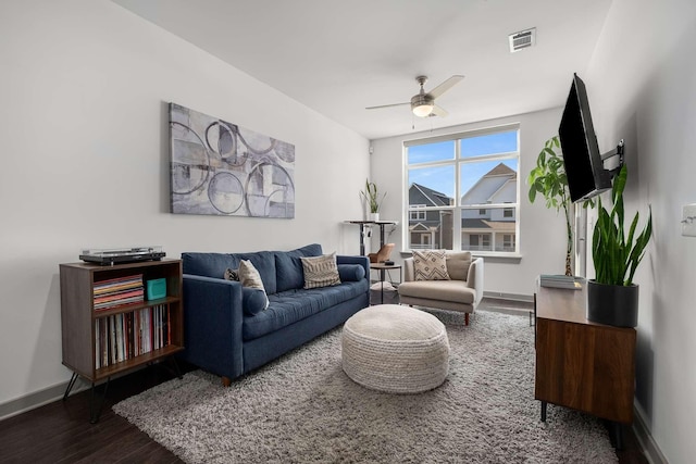 living room featuring a ceiling fan, baseboards, visible vents, and wood finished floors