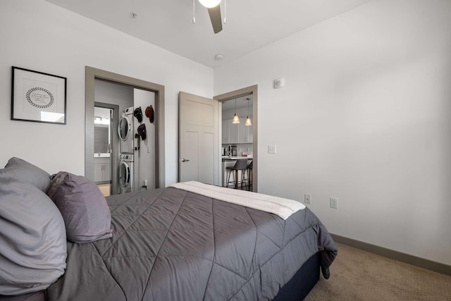 bedroom with baseboards, a ceiling fan, connected bathroom, carpet flooring, and stacked washing maching and dryer