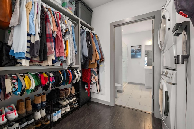 spacious closet with hardwood / wood-style flooring and stacked washer and clothes dryer