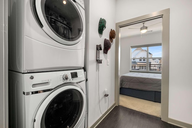 laundry area with baseboards, laundry area, dark wood finished floors, and stacked washer / drying machine