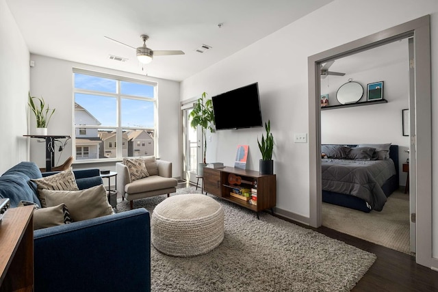 living room with a ceiling fan, visible vents, and wood finished floors