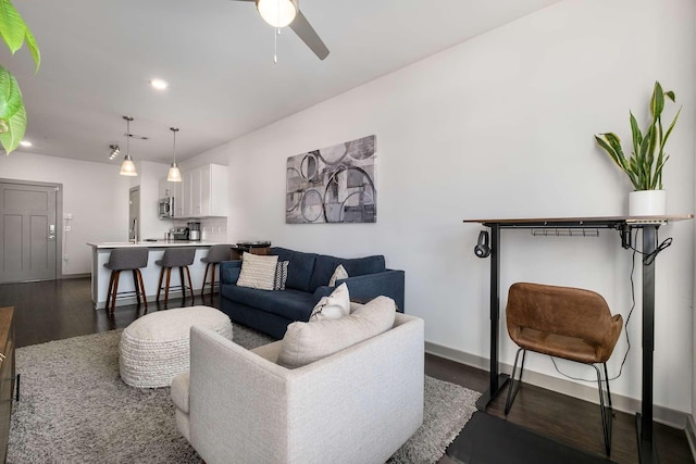 living room featuring a ceiling fan, baseboards, dark wood-type flooring, and recessed lighting