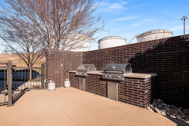 view of patio featuring an outdoor kitchen, fence, and grilling area