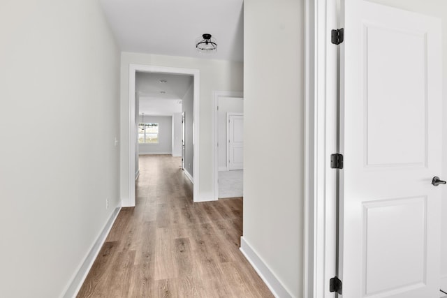 hallway featuring light wood-type flooring and baseboards