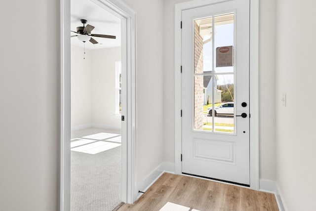 doorway featuring ceiling fan, baseboards, and wood finished floors