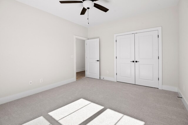 unfurnished bedroom featuring carpet, a closet, ceiling fan, and baseboards