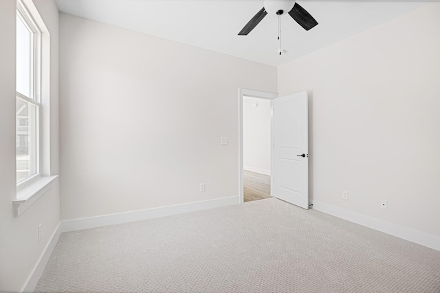 empty room featuring carpet floors, plenty of natural light, baseboards, and ceiling fan