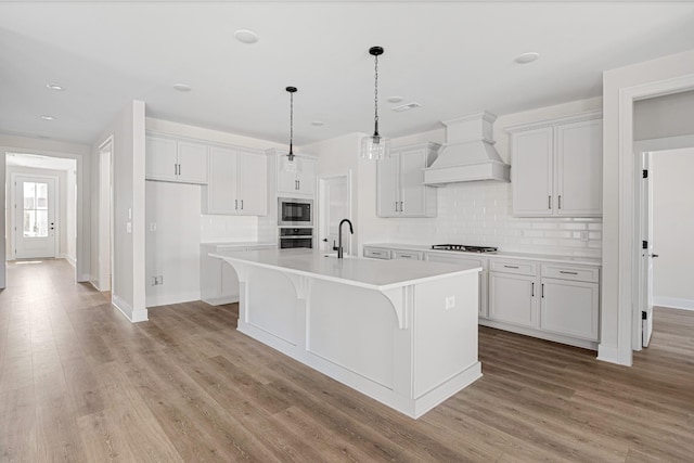 kitchen with gas cooktop, oven, a sink, built in microwave, and custom range hood