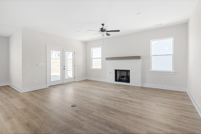 unfurnished living room with light wood finished floors, a brick fireplace, and baseboards