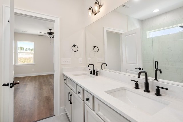 full bath featuring wood finished floors, a sink, a shower stall, and double vanity