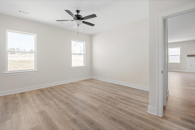 spare room with light wood finished floors, baseboards, visible vents, and ceiling fan