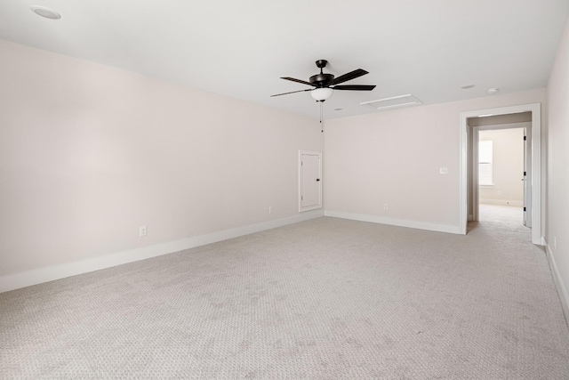 empty room featuring attic access, light carpet, baseboards, and a ceiling fan