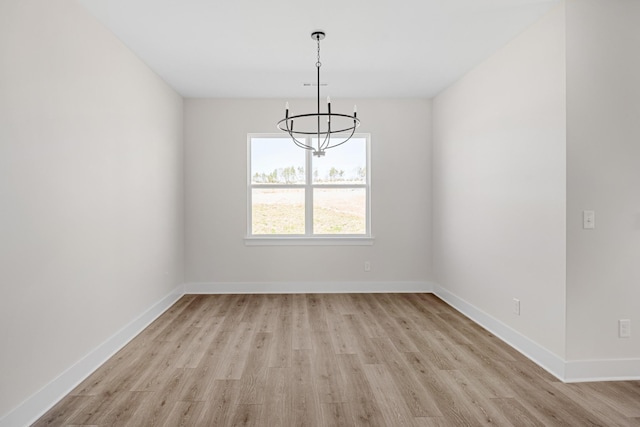 empty room with baseboards, visible vents, light wood-style flooring, and an inviting chandelier