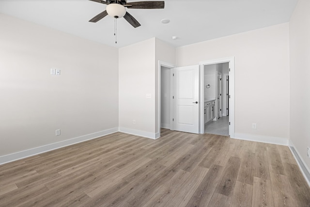 unfurnished bedroom featuring a ceiling fan, baseboards, light wood finished floors, and ensuite bathroom