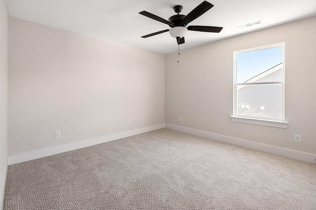 carpeted empty room with a ceiling fan, visible vents, and baseboards