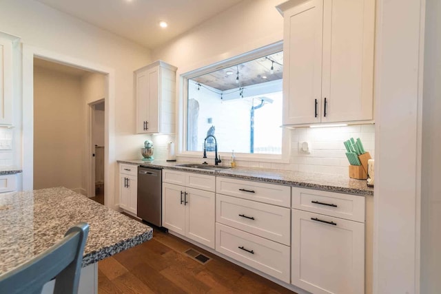 kitchen with light stone counters, stainless steel dishwasher, a sink, and white cabinetry