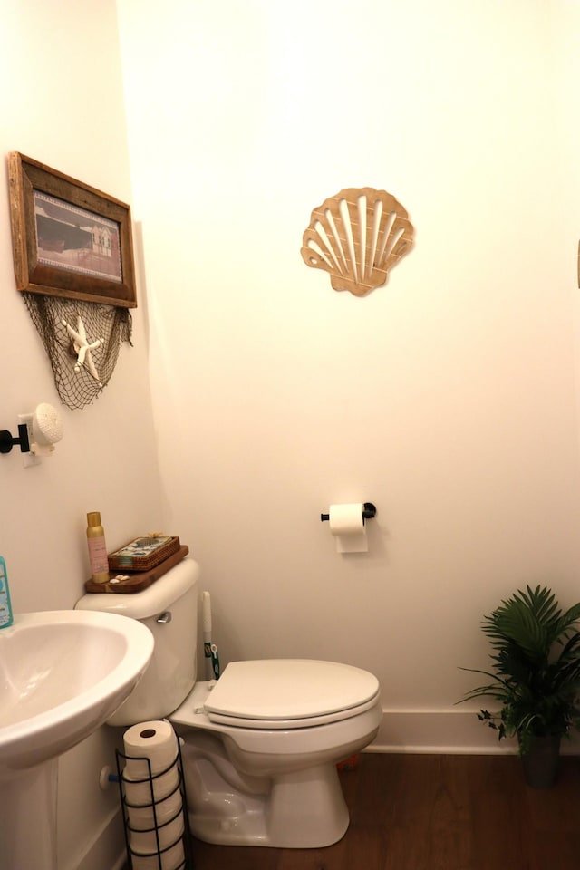 bathroom with baseboards, toilet, and wood finished floors