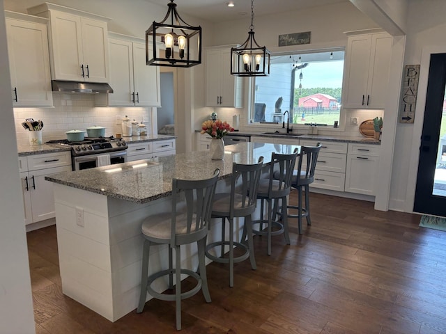 kitchen with gas range, white cabinetry, a breakfast bar, and a center island