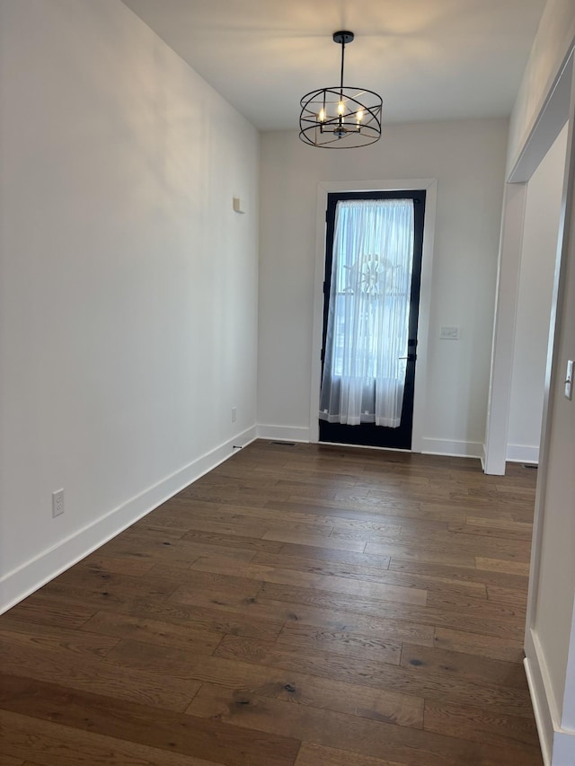 entryway with dark wood-style floors, a notable chandelier, and baseboards