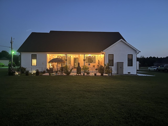 rear view of property featuring crawl space, brick siding, a lawn, and fence