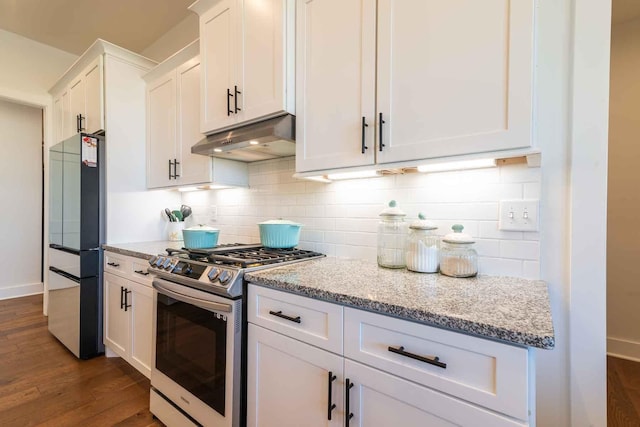 kitchen with light stone counters, under cabinet range hood, white cabinetry, fridge, and stainless steel range with gas cooktop