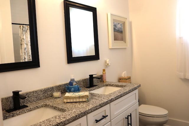 bathroom featuring a sink, toilet, and double vanity