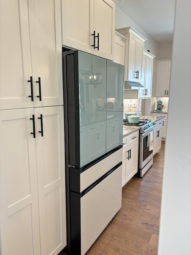 kitchen with freestanding refrigerator, white cabinets, dark wood finished floors, and gas range