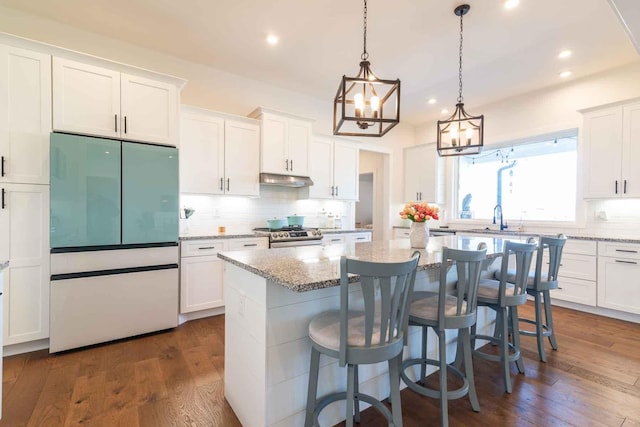 kitchen featuring refrigerator, a center island, and white cabinets