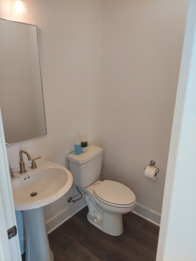 half bathroom featuring toilet, baseboards, and wood finished floors