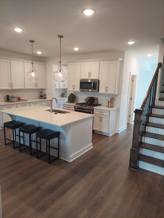 kitchen featuring appliances with stainless steel finishes, white cabinets, light countertops, and a sink