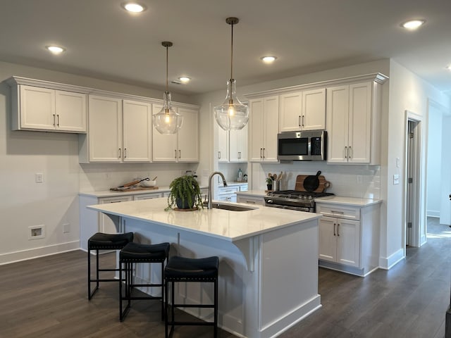 kitchen with a kitchen island with sink, white cabinetry, stainless steel appliances, and a sink