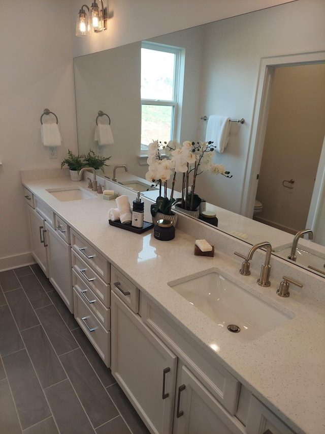 bathroom featuring double vanity, toilet, and a sink