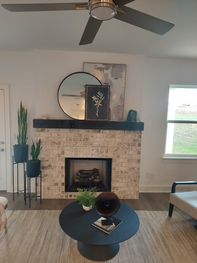 living room featuring a brick fireplace, baseboards, and wood finished floors