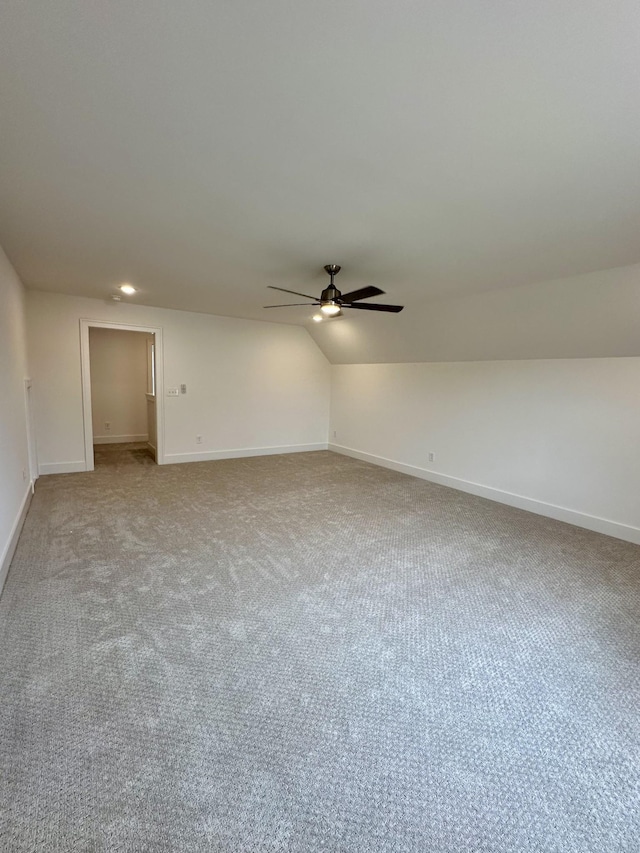 carpeted empty room with baseboards, vaulted ceiling, and a ceiling fan