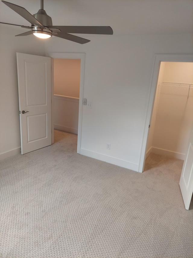 unfurnished bedroom featuring baseboards, a walk in closet, a closet, and light colored carpet