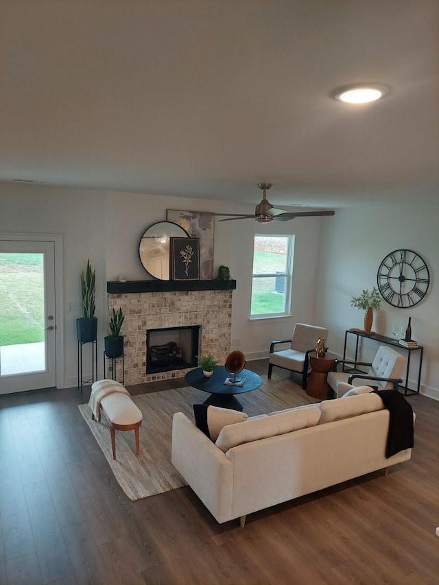 living room featuring a brick fireplace, dark wood finished floors, and baseboards