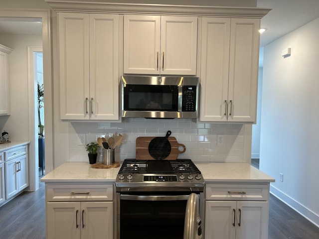 kitchen featuring tasteful backsplash, dark wood-style floors, appliances with stainless steel finishes, light stone counters, and white cabinetry