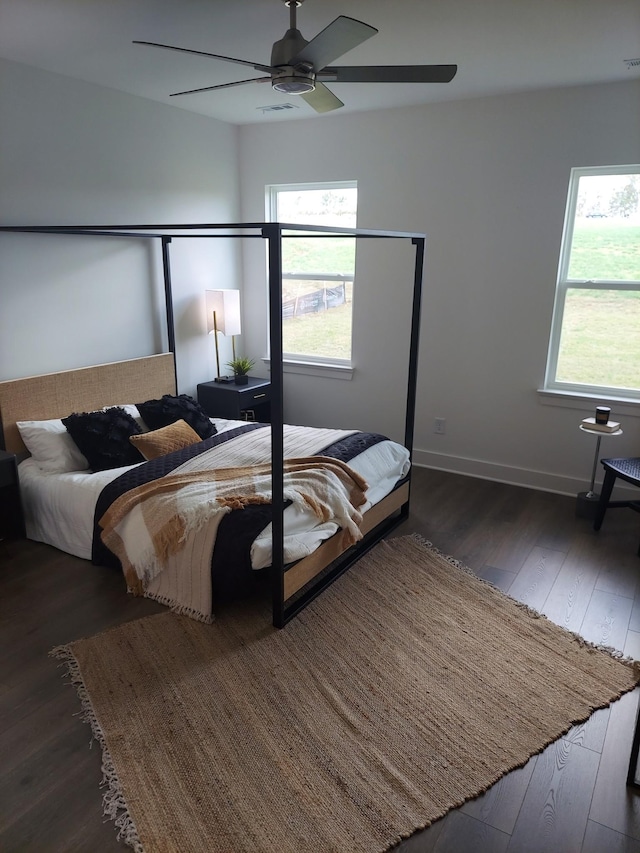 bedroom with ceiling fan, dark wood-style flooring, visible vents, and baseboards