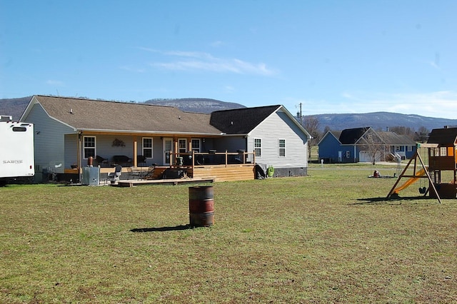 back of house featuring a yard, a playground, and a mountain view