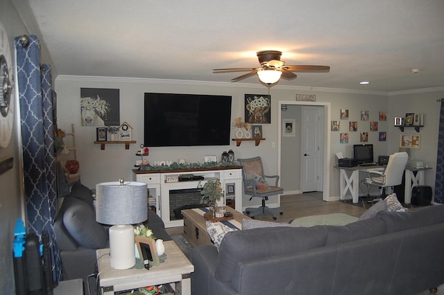 living area featuring a fireplace, wood finished floors, a ceiling fan, baseboards, and ornamental molding