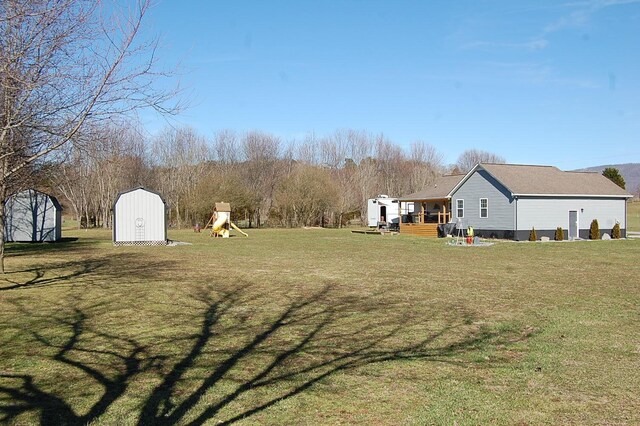 view of yard featuring an outbuilding, a playground, and a storage unit