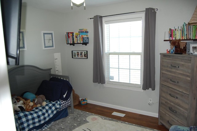 bedroom with multiple windows, baseboards, and wood finished floors