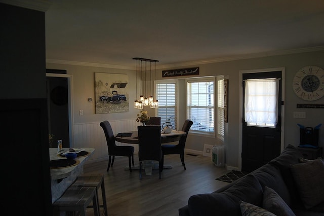 dining area featuring ornamental molding, a wainscoted wall, and wood finished floors