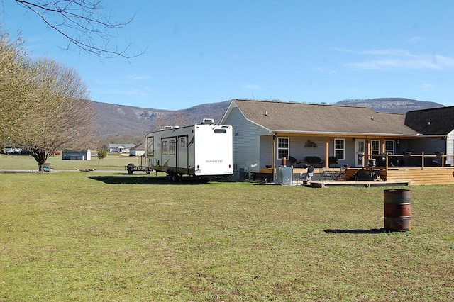 back of house with a mountain view and a lawn