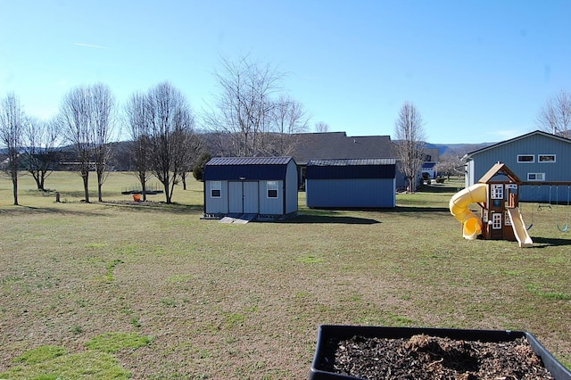 view of yard with a shed, playground community, and an outbuilding