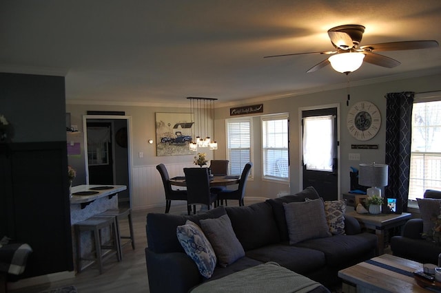 living room with ceiling fan, wainscoting, wood finished floors, and crown molding