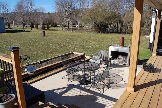 exterior space with a patio area, an outdoor fireplace, outdoor dining area, and a yard