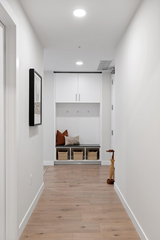 corridor with light wood finished floors, visible vents, recessed lighting, and baseboards