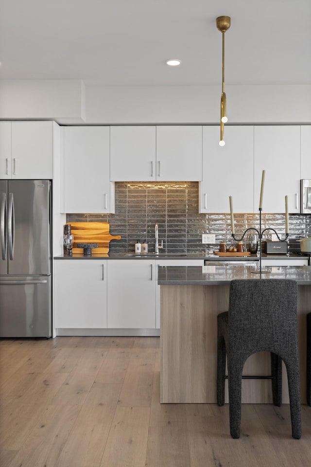 kitchen with white cabinetry, light wood-style flooring, tasteful backsplash, and stainless steel appliances